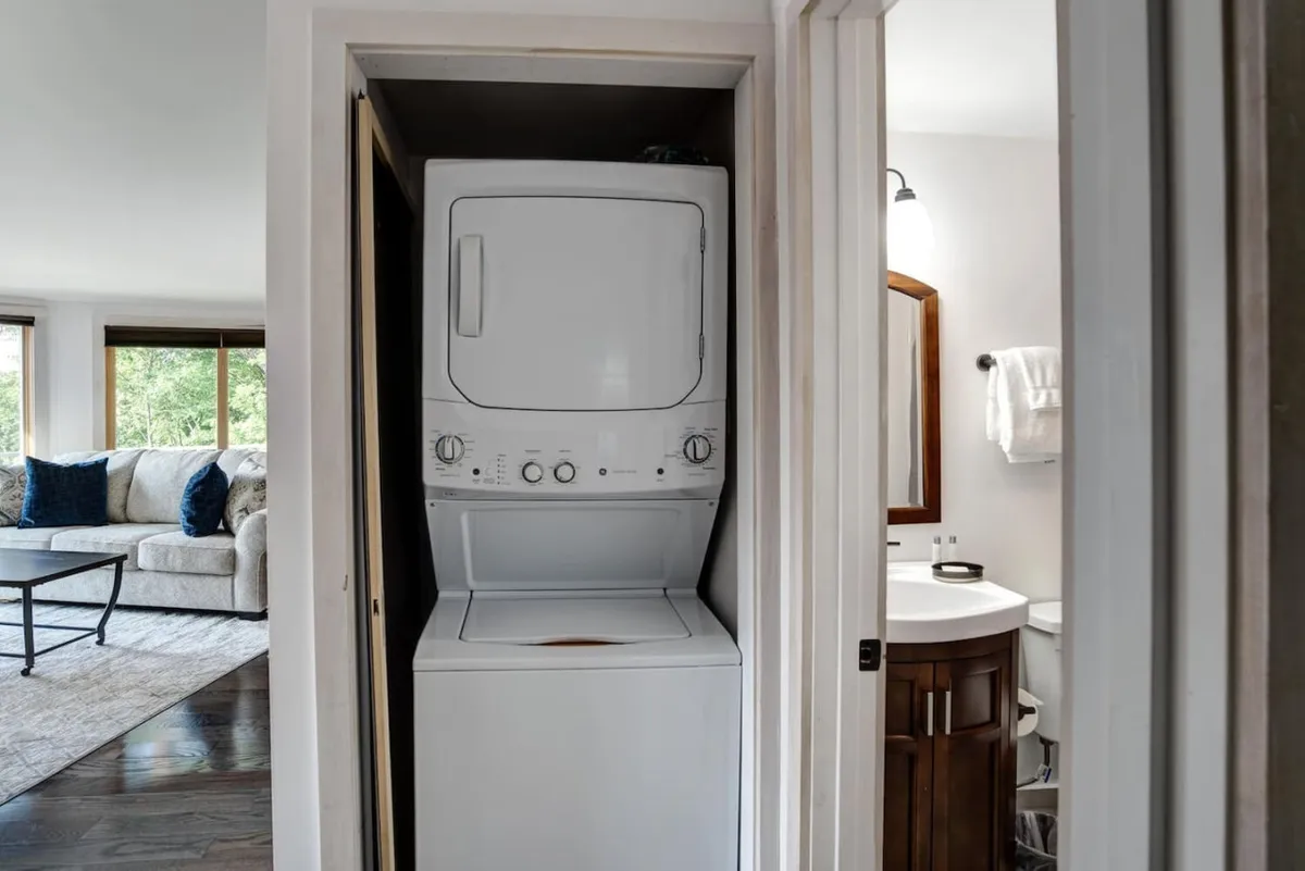 This image showcases a welcoming living area with a comfortable couch, adjacent to a stacked washer and dryer and a bathroom sink. The space feels practical yet inviting, highlighting areas where families can unwind and take care of necessities after a day of outdoor exploration.